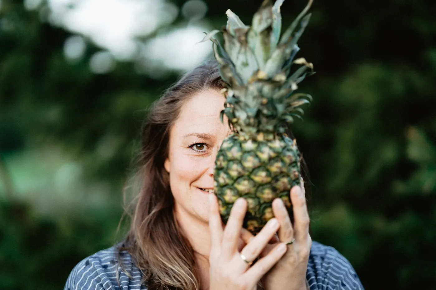 Maggy Horalla hält eine Ananas vor ihr Gesicht