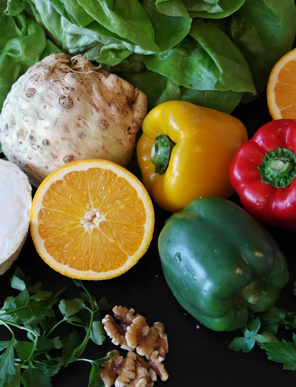 Paprika, Orangen und frisches Gemüse auf dunklem Untergrund