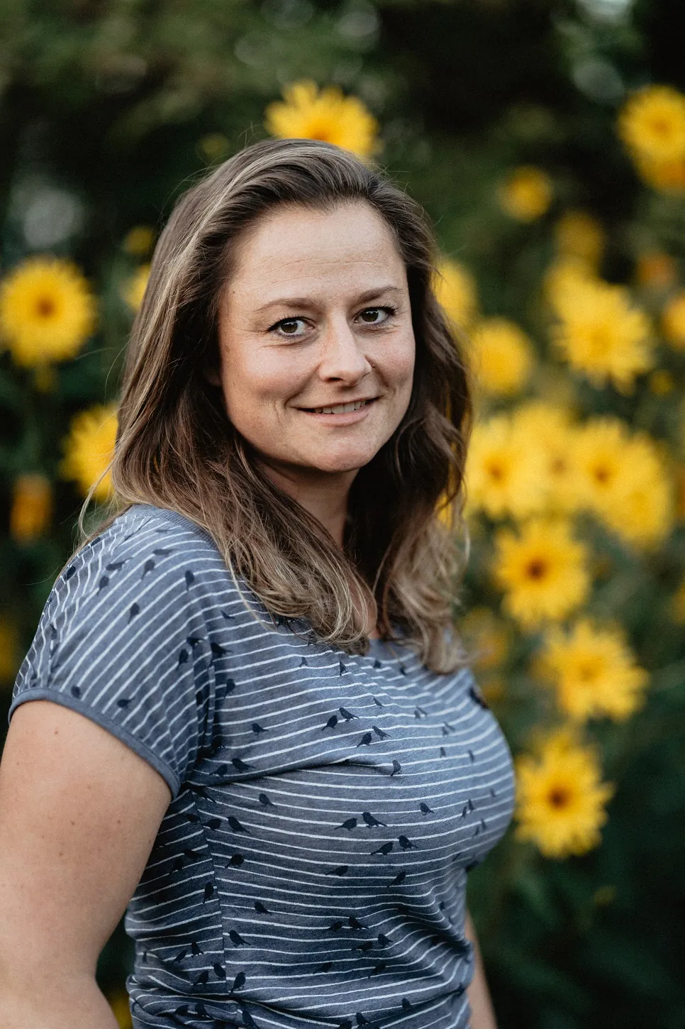 Portrait von Maggy Horalla, zertifizierte Gesundheits- und Ernährungsberaterin, vor gelben Blumen